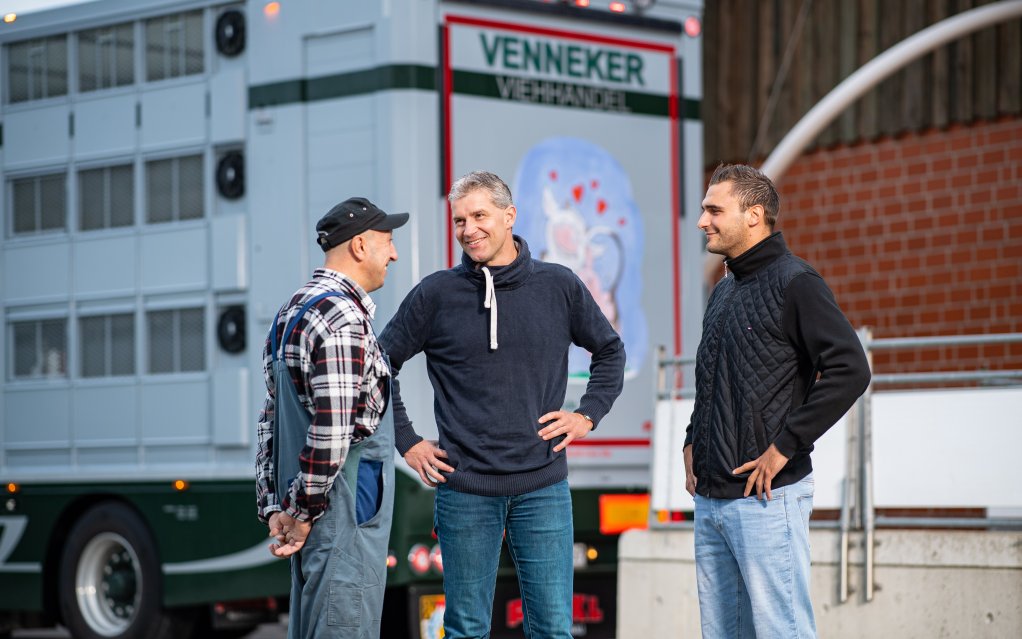 Drei Mitarbeiter vor einem Venneker-LKW, Symbol für nachhaltigen globalen Handel und Effizienz.
